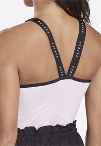 Black and white Reebok sports bra with adjustable straps, featuring a fitted design, smooth fabric, and contrasting logo on the straps.