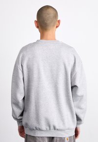 Grå sweatshirt i mjukt tyg, med rund halsringning, långärmar och ribbade ärmslut och nederkant. Diskret märke på den nedre sidan.