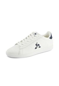 Sneaker bianca con una tomaia in sintetico liscia, accentuata da un tallone blu navy e lacci bianchi piatti. Presenta un logo sul lato e cuciture decorative.