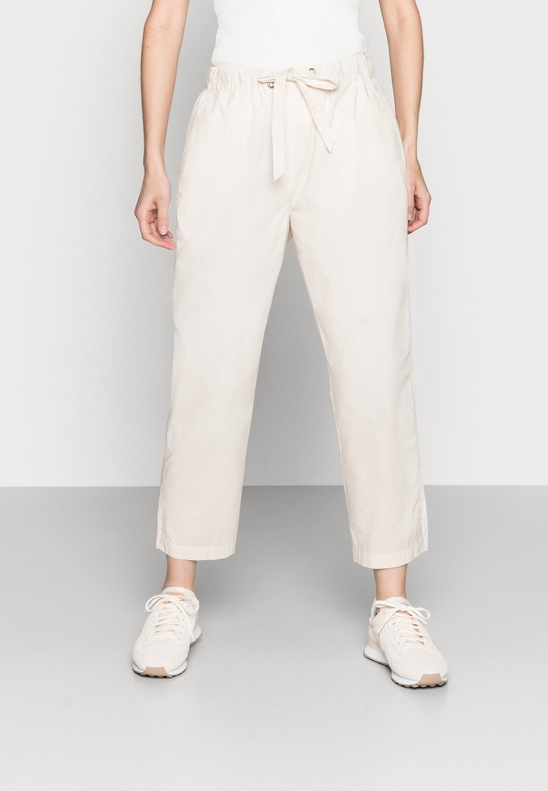 Pantalon léger de couleur crème avec une taille élastique et un cordon de serrage, doté d'une coupe droite et d'un léger éclat.