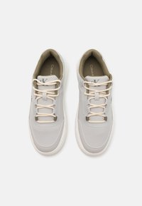 Sneaker grigie chiare con una tomaia in tessuto liscio, lacci beige, colletto imbottito beige e suole in gomma bianca. Presenta un logo sul lato.
