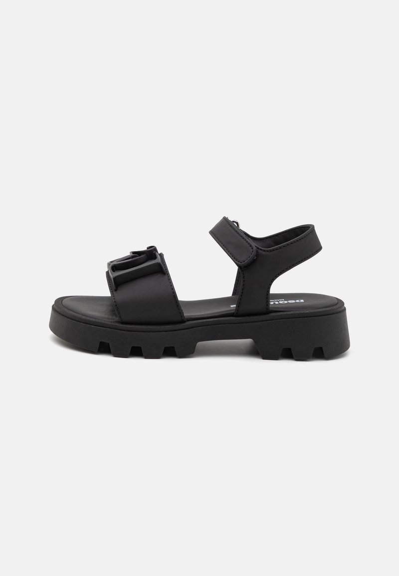 Mustad sandle, mille pehme tallaga, reguleeritavate rihmadega ja tekstureeritud viimistlusega. Ülaservas on kaks pandla aksessuaari. Kummist tallad hea haarde tagamiseks.