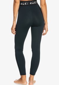 Leggings neri da performance con vita alta, caratterizzati dalla scritta bianca "ROXY", texture liscia e vestibilità aderente, progettati per l'abbigliamento attivo.