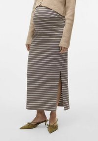 Zwangere maxi rok in bruin met witte horizontale strepen, met een zijsplit. Gekoppeld aan olijfgroene muiltjes met een spitse neus.