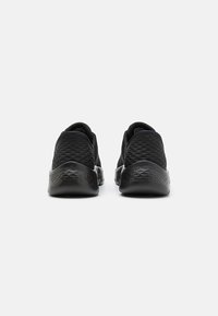 Baskets de sport noires avec un dessus en mesh texturé et une semelle en caoutchouc lisse, dotées d'un bout rond et d'un col rembourré pour plus de confort.