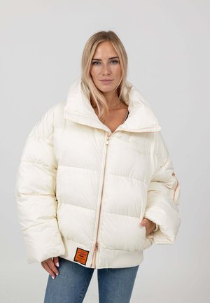 Kurtka puchowa w kolorze off-white, posiadająca wysoki kołnierz, zapięcie na zamek błyskawiczny oraz ściągacze na mankietach. Wyjątkowa pomarańczowa metka na dole.
