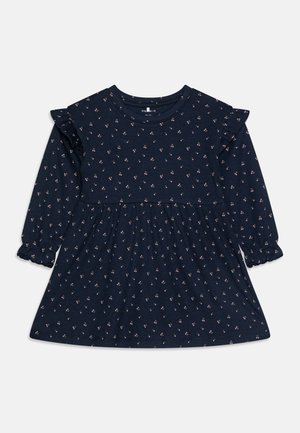 Rochie lungă de culoare bleumarin, cu un model texturat de flori mici, accente fâlfâitoare la umeri și fustă plisată cu manșete elastice.