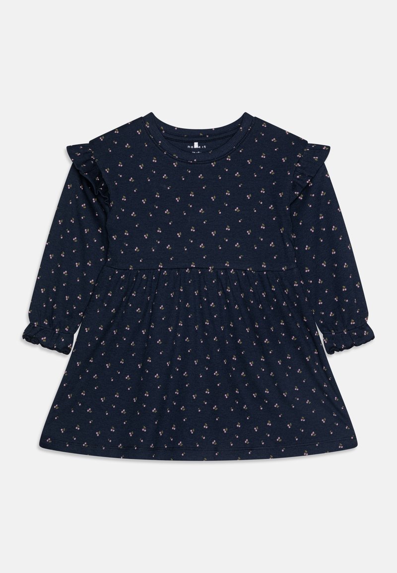 Tamsiai mėlyna suknelė ilgomis rankovėmis su tekstūruotu mažųjų gėlių raštu, raukiniais ant pečių ir rauktu sijonu su elastiniais rankogaliais.