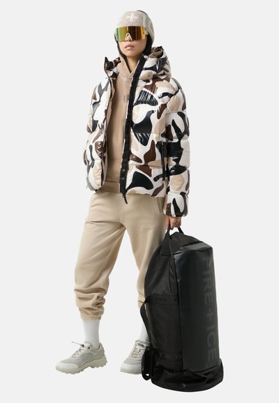 Pufferjack in een glanzend zwart, beige en bruin camo patroon; beige hoodie; beige joggers; zwarte sporttas met de tekst "FIRE + ICE".