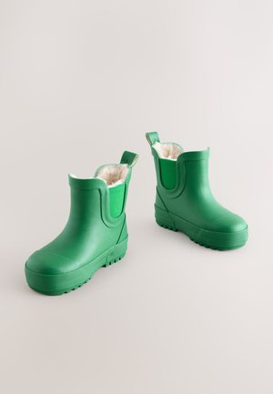 Bottes en caoutchouc vert avec une texture lisse, une doublure moelleuse, hauteur cheville, languettes de tirage, et une semelle extérieure rainurée pour l'adhérence.