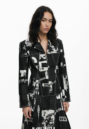 Black and white printed jacket with a fitted design, notched collar, long sleeves, and visible stitching, featuring a collage of text and images.