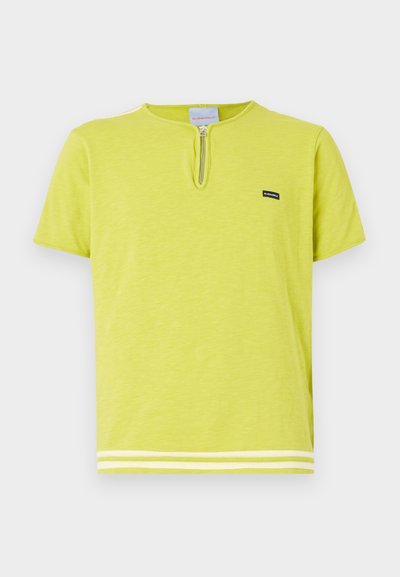 Gaiši zaļš T-krekls, izgatavots no mīksta auduma, ar rāvējslēdzēja kakla izgriezumu, īsām piedurknēm un baltām svītrām apakšmalā.