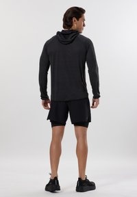 Maglietta leggera a maniche lunghe, nera, con cappuccio e tessuto a trama, abbinata a pantaloni corti sportivi neri e scarpe da corsa nere.