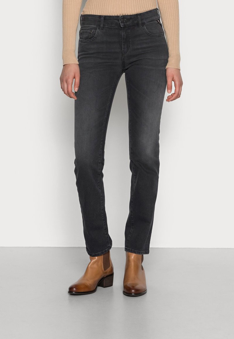 Slim-fit svarta jeans med subtila blekningar, klassisk fem-fickdesign och dragkedja. Matchade med bruna ankelskor.