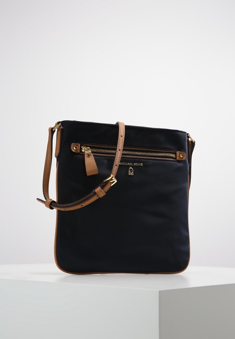 Borsa a tracolla nera in nylon con dettagli in pelle color cannella, dotata di una tasca frontale con zip e tracolla regolabile. Dettaglio del logo dorato sulla parte anteriore.