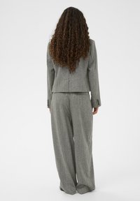 Siva obleka z oprijetim blazerjem in hlačami širokih hlačnic. Material ima subtilno teksturo. Blazer ima dva gumba in dolge rokave.