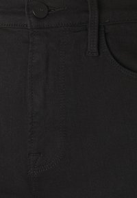 Jeans de mezclilla negra con una textura suave, que cuentan con un cierre de botón, bolsillo lateral y costuras visibles a lo largo de las costuras.