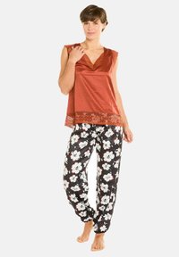 Haut en satin rouille avec dentelle, associé à un pantalon de pyjama noir à fleurs comportant des fleurs blanches et rouges. Coupe décontractée, longueur cheville.