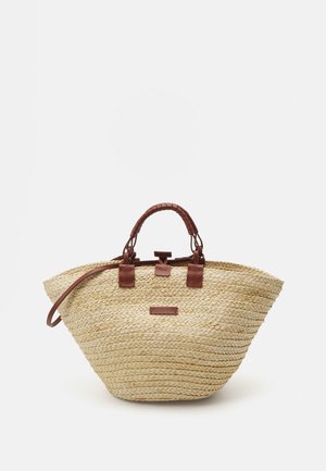 Spleciona torba z trawy w szerokim, okrągłym kształcie. Brązowe skórzane uchwyty i akcenty, z prostokątną metką z przodu.