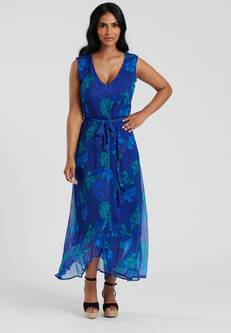 Blommig maxiklänning i blått tyg med gröna mönster, djup V-ringning, ärmlös design, bälte i midjan och flytande nederkant.