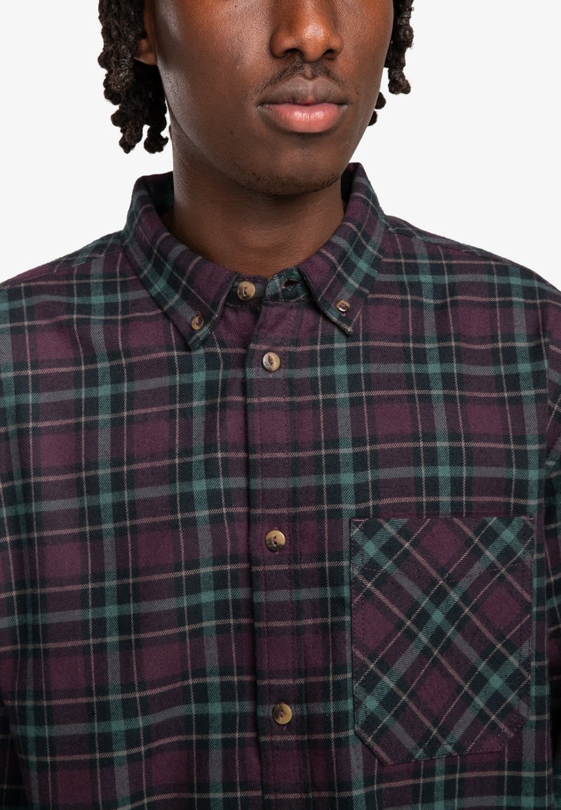 Camicia a quadri con tonalità di viola scuro e verde, colletto a bottoni e taschino sul petto con motivo a quadri abbinato. Tessuto morbido.