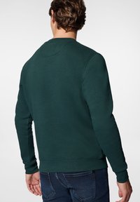 Ciemnozielony nadruk z okrągłym dekoltem i długimi rękawami, o gładkiej fakturze. Posiada ściągacze na mankietach i u dołu, zapewniające dobre dopasowanie.