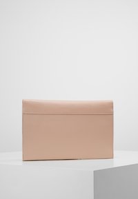 Beige läderkuvert med en slät yta och rektangulär form. Har en vikbar flik och en minimalistisk design. Ingen synlig hårdvara.