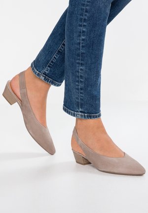 Sandały damskie na obcasie w miękkiej, taupe zamszowej skórze, z noskiem w kształcie szpica i niskim obcasem o stylu stack. Noszone z ciemnoniebieskimi dżinsami z podwiniętymi nogawkami.