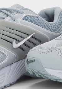 Light blue athletic shoes with mesh fabric, rubber sole, and silver hardware. Features a prominent Nike logo and textured accents.