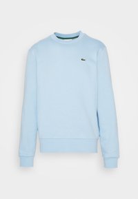 Sweatshirt bleu clair en tissu doux, avec un col rond, des manches longues et un petit logo de crocodile vert sur la poitrine.