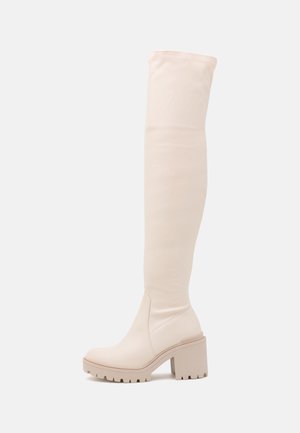 Bottes beige au-dessus du genou avec talon haut épais et semelle à crampons, dessus en tissu lisse, coutures latérales et style à enfiler.