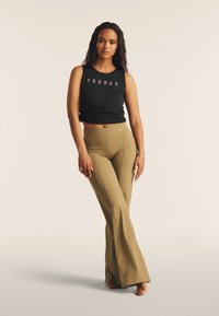 Top senza maniche nero con la scritta "FREDDY", abbinato a leggings a palazzo verde oliva, a vita alta. Texture liscia, design aderente.