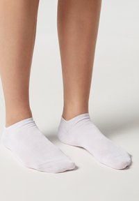 Vita, låga strumpor i mjukt material, med sömlös design och en slät yta samt minimal ribbning vid öppningen.