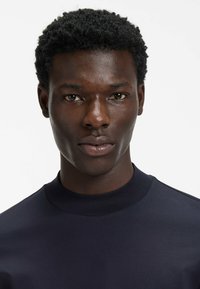 Marineblaues langärmeliges Hemd mit hohem Kragen, glatter Textur, figurbetontem Design und ohne sichtbare Muster oder Akzente.