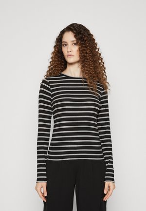 T-shirt à manches longues noir avec des rayures horizontales blanches, présentant une texture côtelée et un col rond. Associé à un pantalon noir.