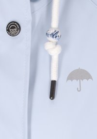 Šviesiai mėlynos spalvos lietpaltio audinys su sidabrine skėčio grafika. Yra balta pintinė virvelė su dekoratyvine mėlyna ir balta karoliuku.