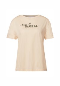 Camiseta color crema con mangas cortas enrolladas y un cuello redondo, que presenta un texto en negro: "TU CAMINO VALIOSO INFINITO / POTENCIAL."
