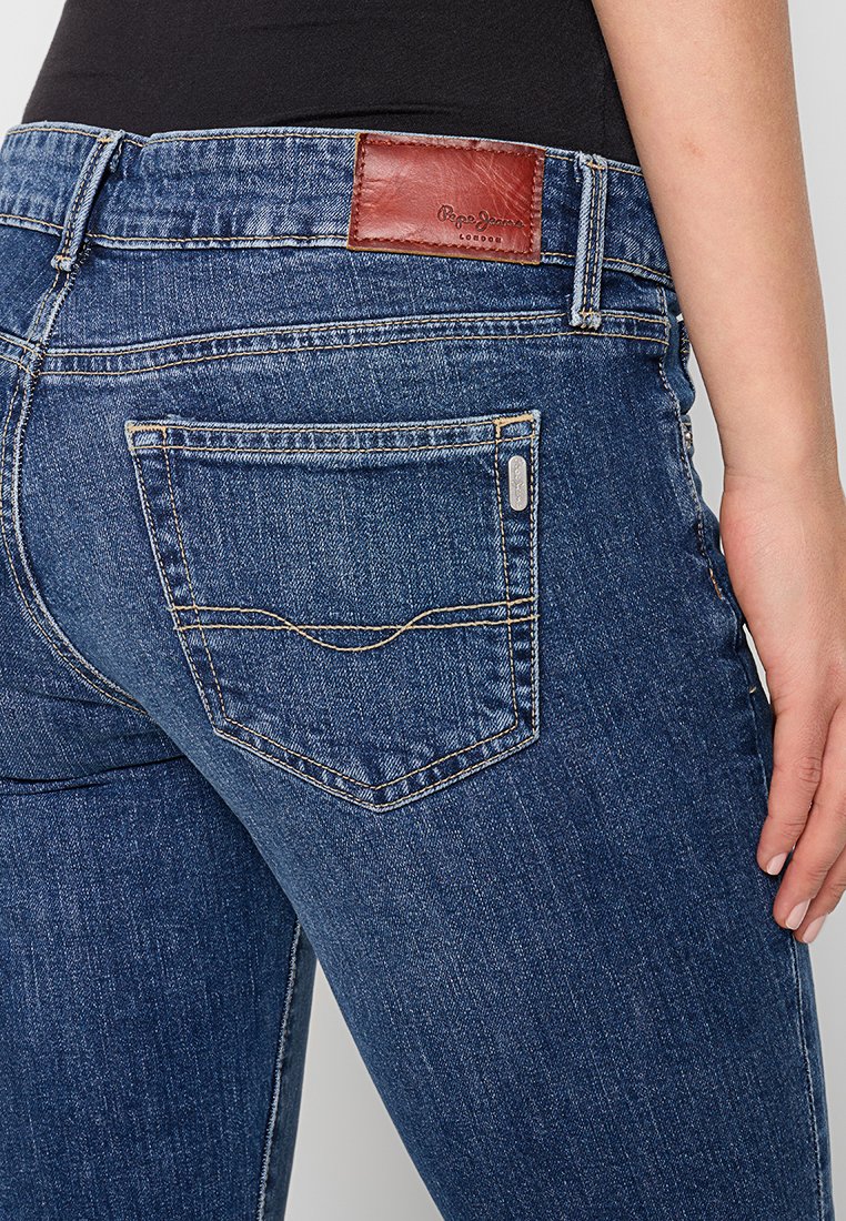 Dunkelblaue Jeans aus Denim mit einem braunen Lederlabel am Bund, standardmäßigen Gesäßtaschen mit kontrastierendem Nähen und einem schlanken Schnitt.