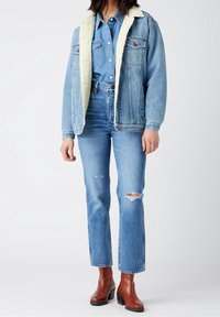 Denim jacket with fleece collar, light blue, paired with light blue ripped jeans and brown ankle boots with a block heel.