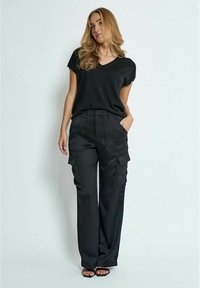 T-shirt nero con scollatura a V e maniche corte abbinato a pantaloni cargo neri con ampie tasche anteriori e laterali, tessuto liscio e forma elegante.