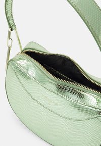 Groene metallic handtas met een slangenhuidtextuur, ritsluiting en gouden hardware. Het interieur is zwart, wat een strak contrast biedt.