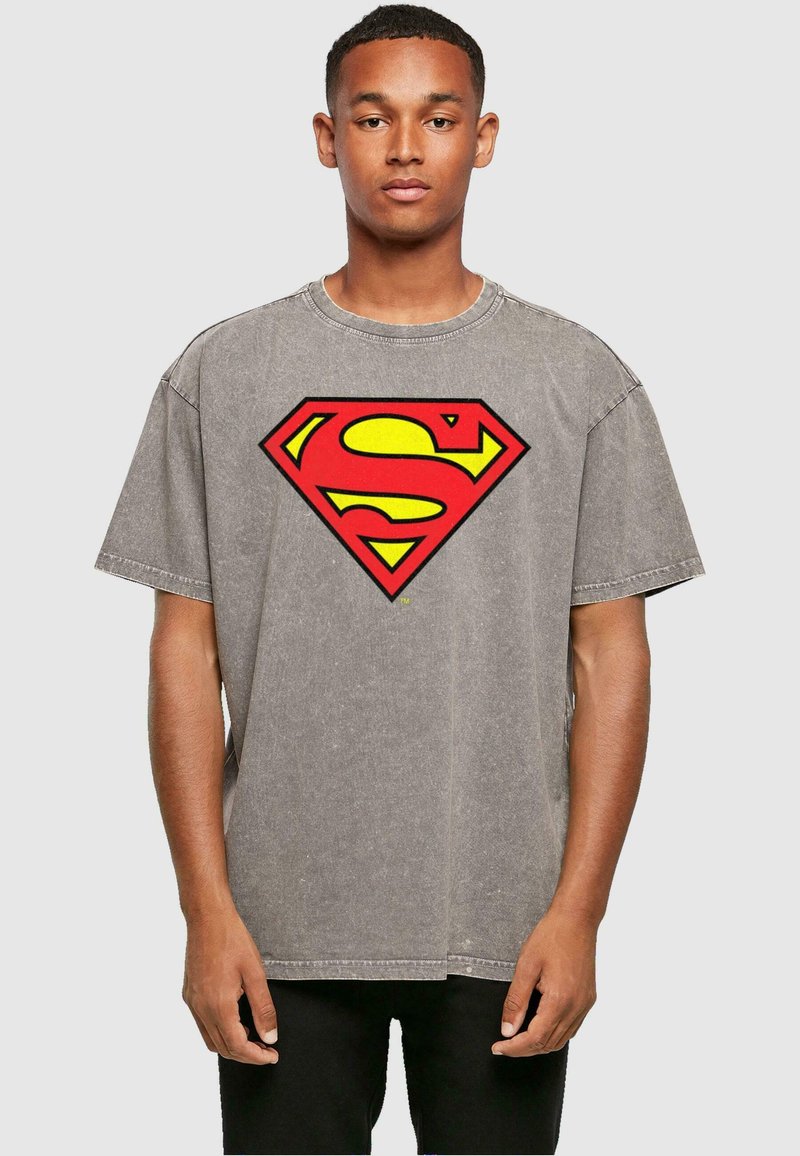 Grijze oversized t-shirt gemaakt van katoen, met een groot rood en geel Superman-logo op de voorkant; korte mouwen en ronde halslijn.