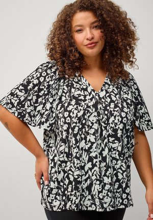 Zwart-witte blouse met bloemmotief, voorzien van een V-hals, ontspannen korte mouwen en een gestructureerde stof. Losse pasvorm met zichtbare bloemaccenten.