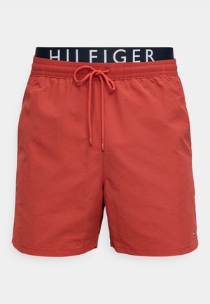 Κόκκινα ανδρικά μαγιό με κορδόνι στη μέση και ορατή μαύρη ζώνη μέσης με την επωνυμία "HILFIGER" σε απλό φόντο.