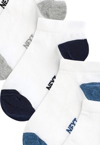 Chaussettes blanches à chevilles avec des talons colorés en gris, bleu marine et bleu. Présentent des bords côtelés et un petit logo de marque sur le côté. Texture en tricot douce.
