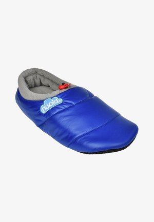 Zapatilla azul acolchada con forro de forro polar gris, puntera redondeada y suela negra de goma. Presenta un botón rojo y un logotipo azul.
