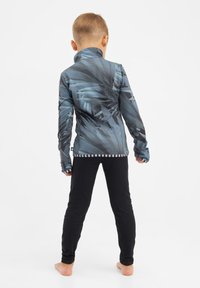 Langärmliges Zip-Up-Shirt in blau-grau mit abstrakten Blättermustern, kombiniert mit schwarzen Leggings; glatte Textur und taillierte Passform.