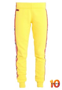 Geel joggingbroek van zachte stof, met een rode zijstripe met tekst. Elastische tailleband en taps toelopende boorden.