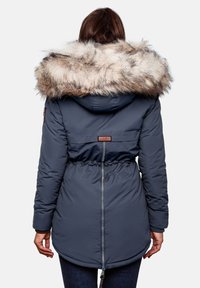 Veste rembourrée bleu marine avec une capuche en fausse fourrure douce, une taille à lien de serrage, des poches latérales et un design mi-long. Dispose d'une fermeture éclair.