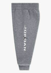 Harmaat collegehousut pehmeästä kankaasta, joissa on joustava vyötärö, kapenevat lahkeet ja valkoinen "JORDAN"-teksti mustalla logolla sivulla.